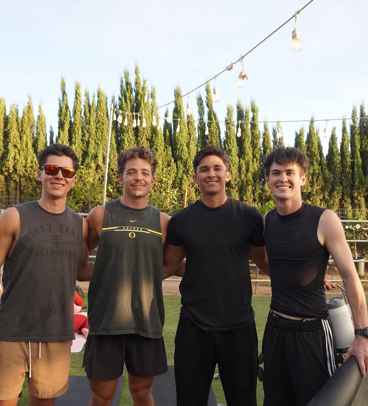 Four friends smiling together on the lawn after a Pilates class