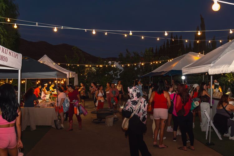 Guests strolling between tents at a night market lit with string lights