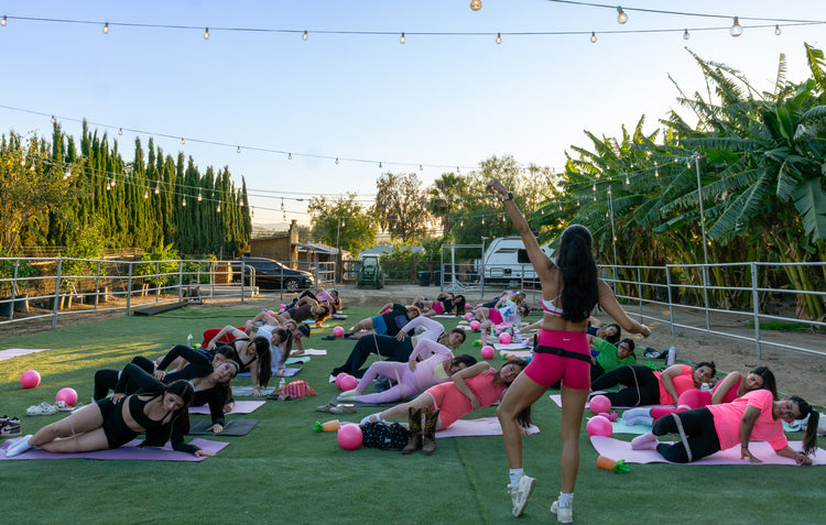 An instructor leading a group Pilates class on the ranch lawn