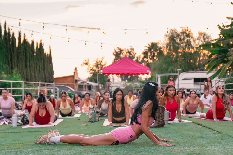 Guests stretching through a sunset Pilates class on the lawn under string lights